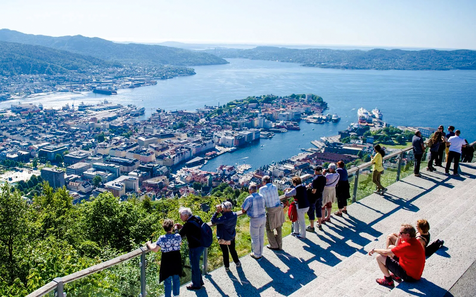 Tourists enjoying the view of Bergen, Norway, from Mount Fløyen's scenic viewpoint.
