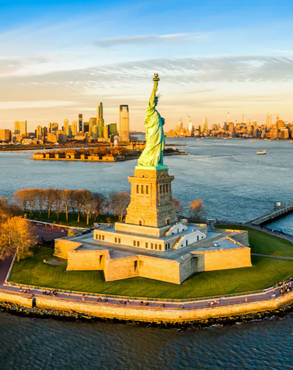 Aerial view of the Statue of Liberty with New York City skyline in the background.