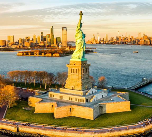 Aerial view of the Statue of Liberty with New York City skyline in the background.