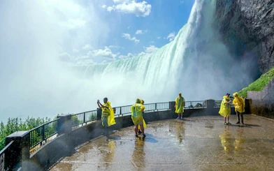 Visitors in yellow ponchos at Niagara Falls viewpoint, capturing the waterfall.