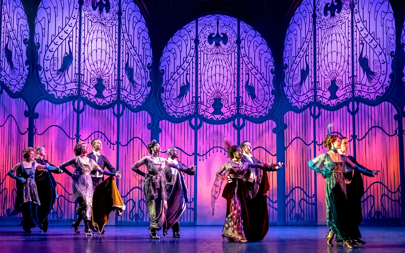 Performers dancing on stage in a scene from "My Fair Lady" with ornate backdrop.