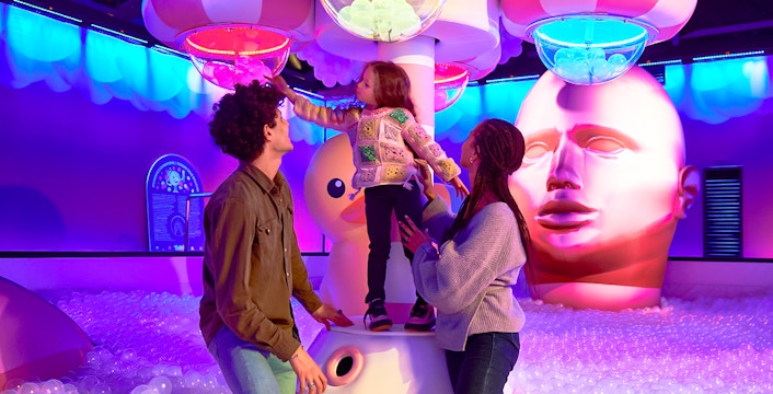 Family exploring Bubble Planet exhibit in Seattle with colorful lights and interactive displays.