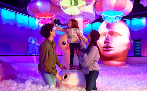 Family exploring Bubble Planet exhibit in Seattle with colorful lights and interactive displays.