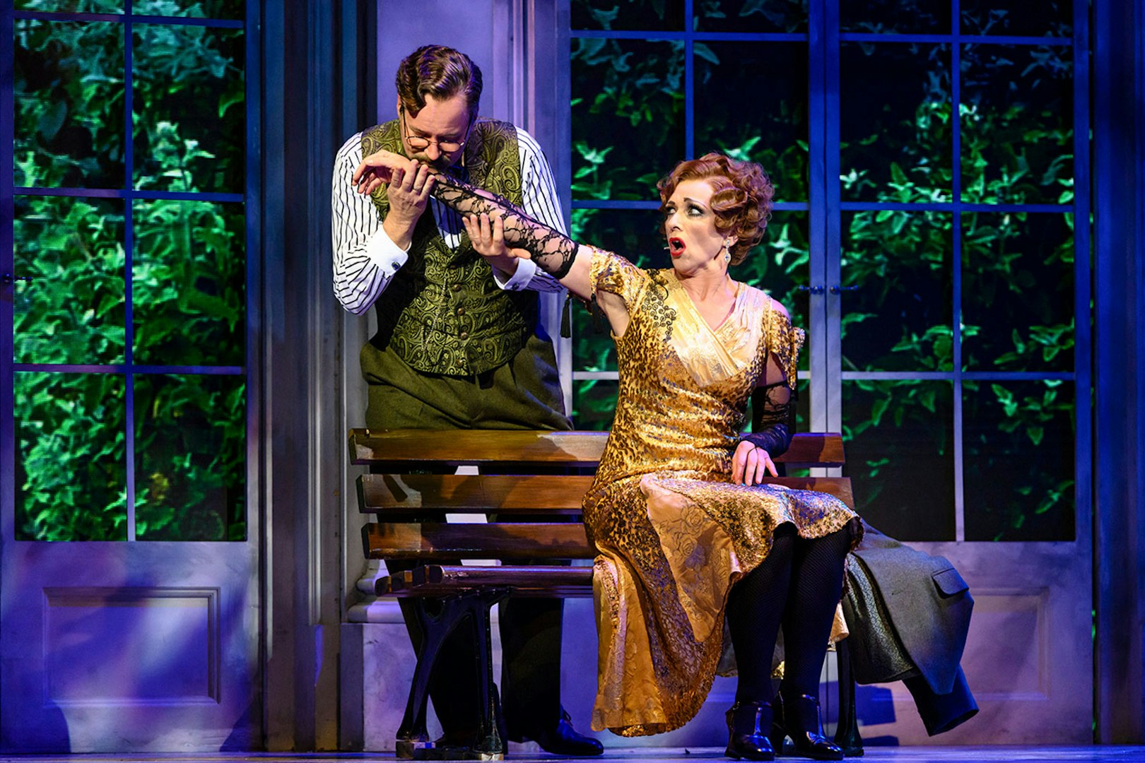 Actors performing a scene from Anastasia on stage, with a man kissing a woman's hand.