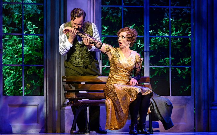 Actors performing a scene from Anastasia on stage, with a man kissing a woman's hand.