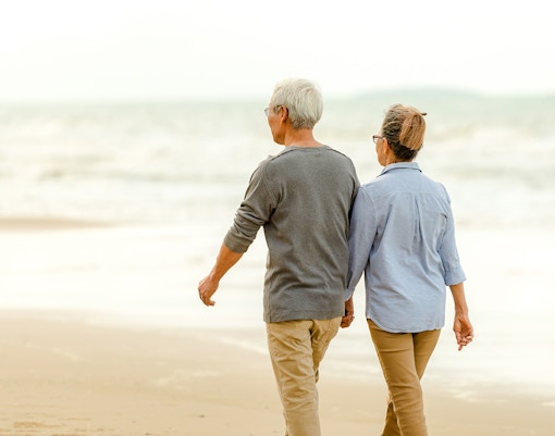 Tourists walking along a sandy beach with palm trees in the background, Miami, Florida.