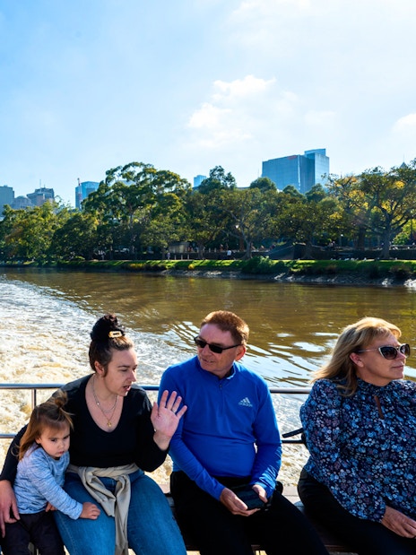 People enjoying a Yarra River cruise with Melbourne skyline in the background.