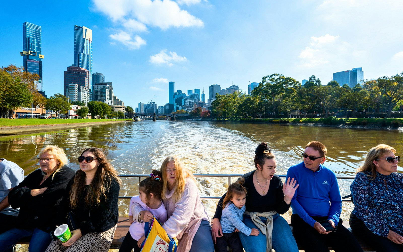 People enjoying a Yarra River cruise with Melbourne skyline in the background.