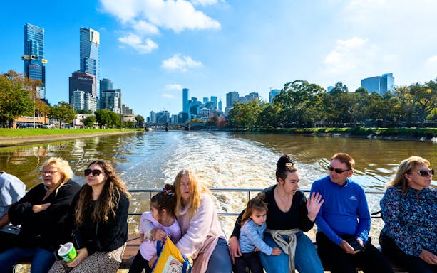People enjoying a Yarra River cruise with Melbourne skyline in the background.