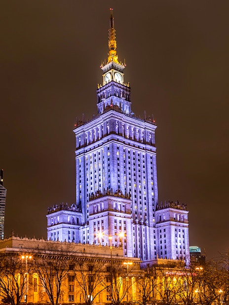Palace of Culture and Science illuminated at night in Warsaw, Poland.