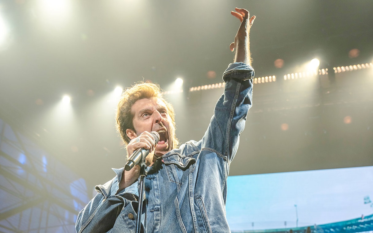 Performer singing passionately on stage at Just for One Day event.