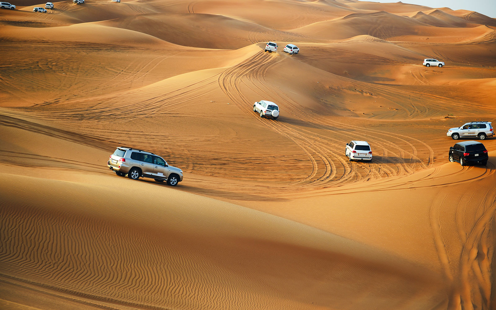 4x4 vehicles driving on sand dunes in Doha desert.