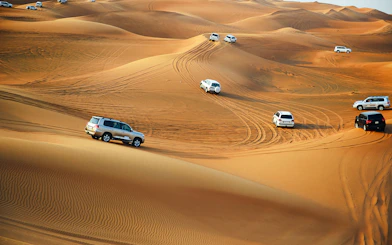 4x4 vehicles driving on sand dunes in Doha desert.