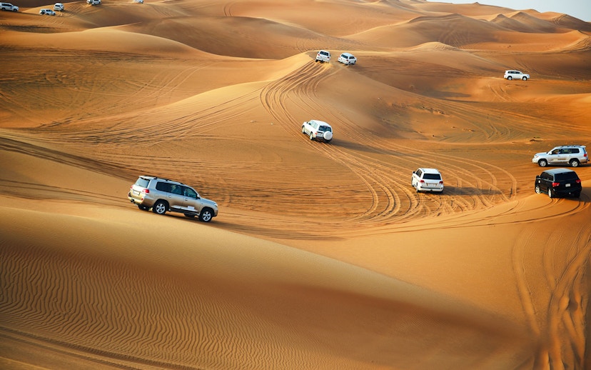 4x4 vehicles driving on sand dunes in Doha desert.