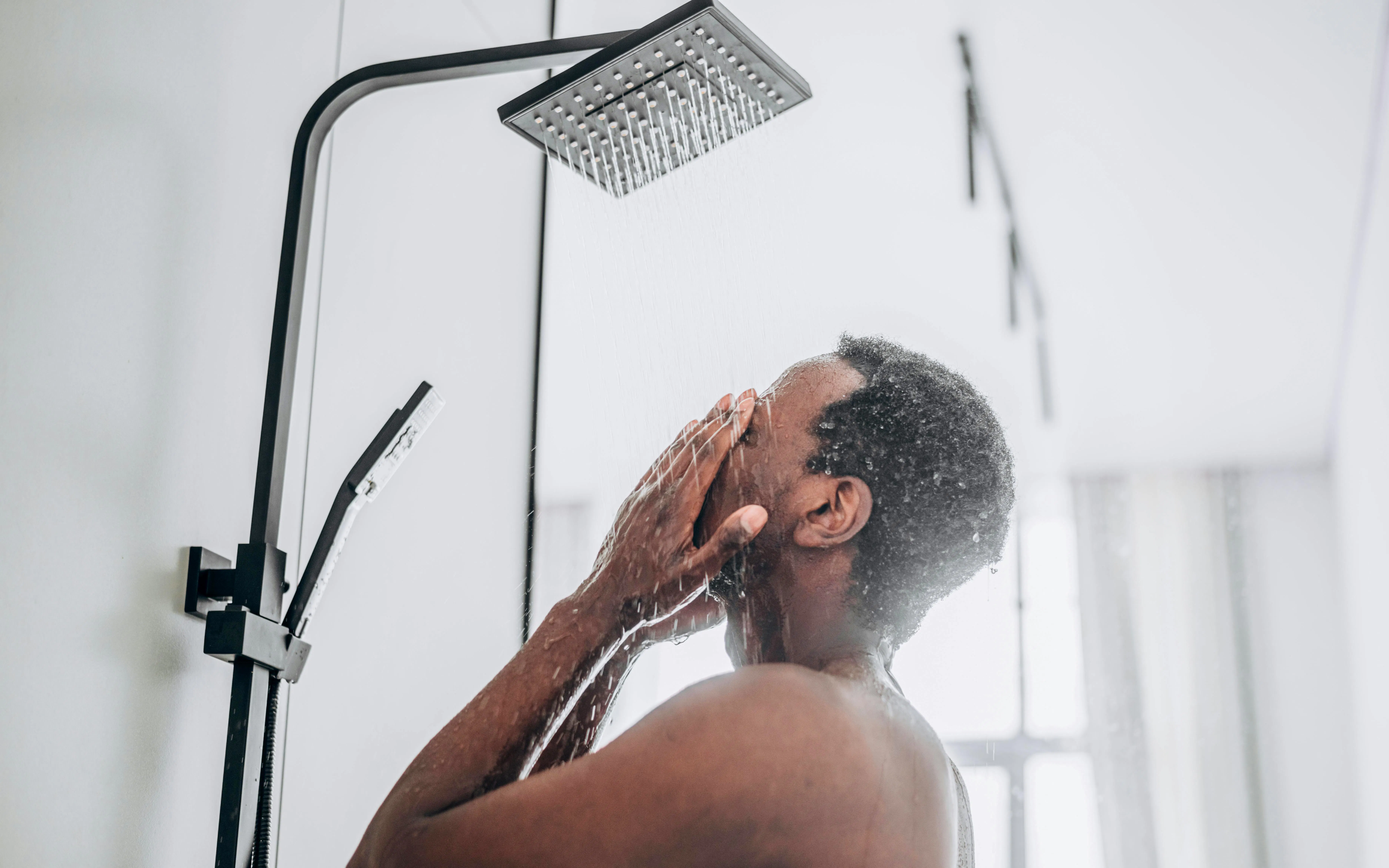 Person enjoying a refreshing shower in a modern bathroom.