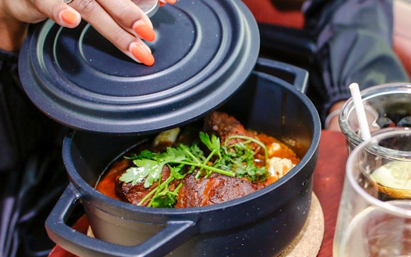 Person lifting lid off a dish on Paris En Scène Dinner Cruise on the Seine.