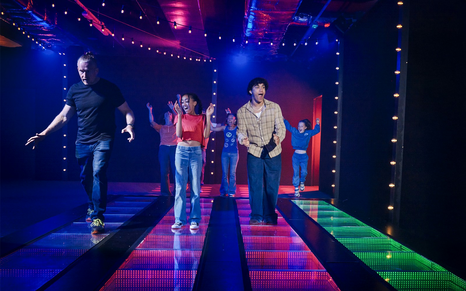 Participants on a lit glass bridge at Squid Games experience in London.