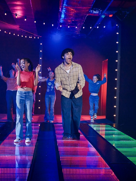 Participants on a lit glass bridge at Squid Games experience in London.