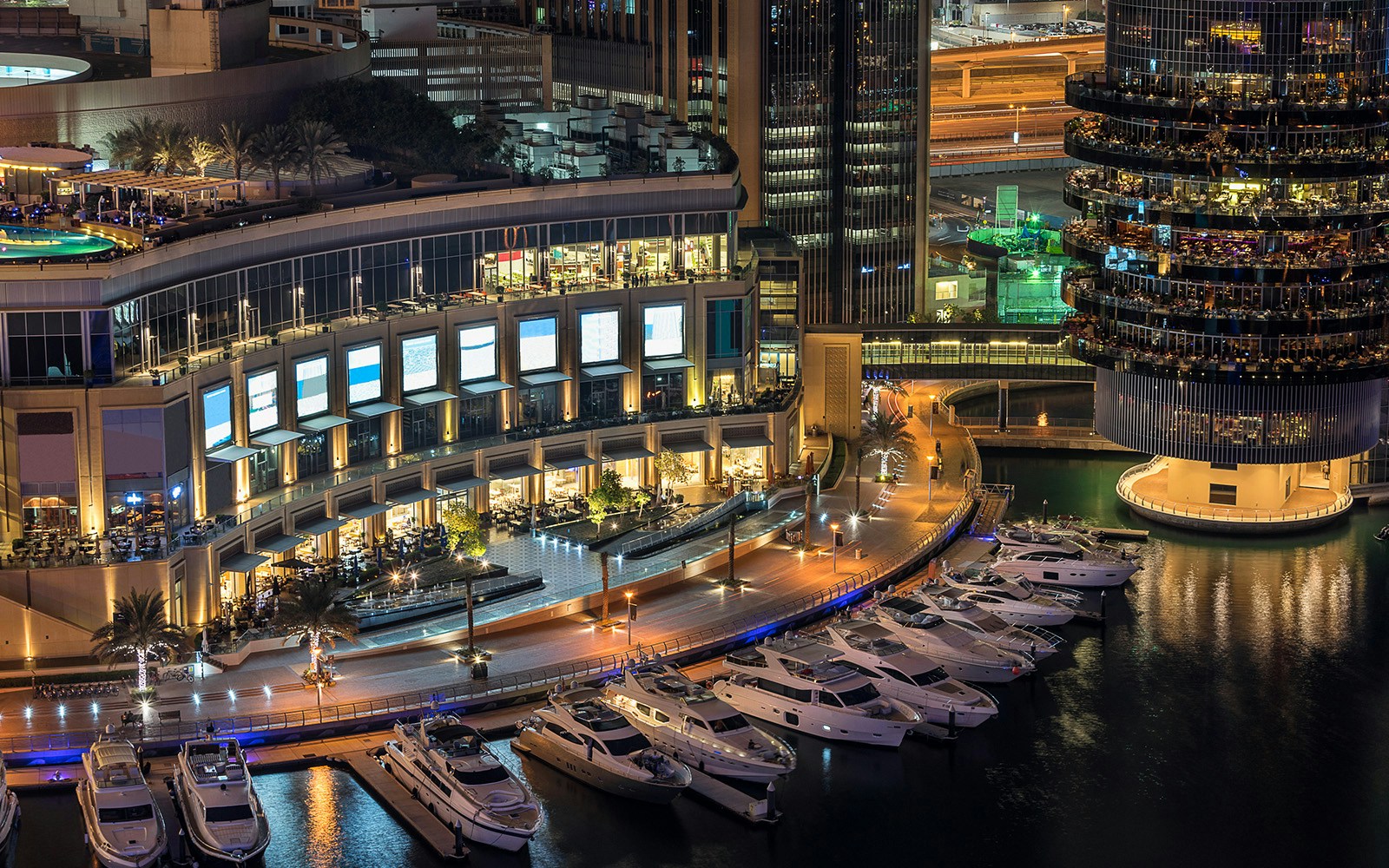 Dubai Marina Mall waterfront with yachts docked at night.