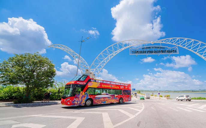 Hop-On Hop-Off bus at Tuan Chau entrance, Ha Long Bay, under a clear blue sky.