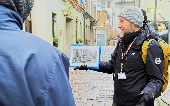 Tour guide in Krakow showing historical photo during Schindler’s Story tour in Kazimierz district.