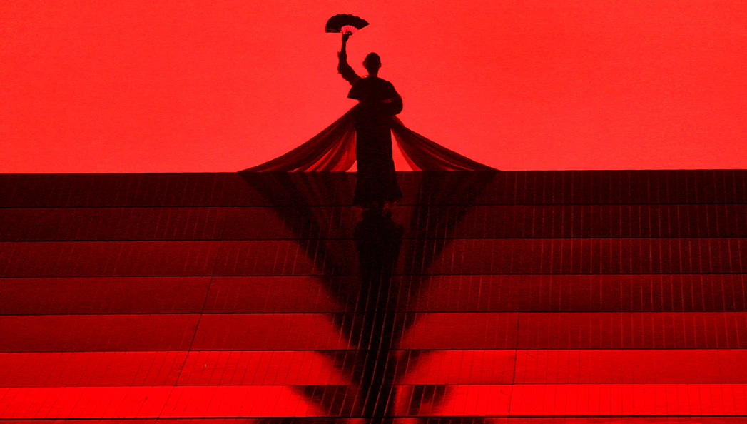 Silhouette of a performer holding a fan on stage during Madama Butterfly opera.