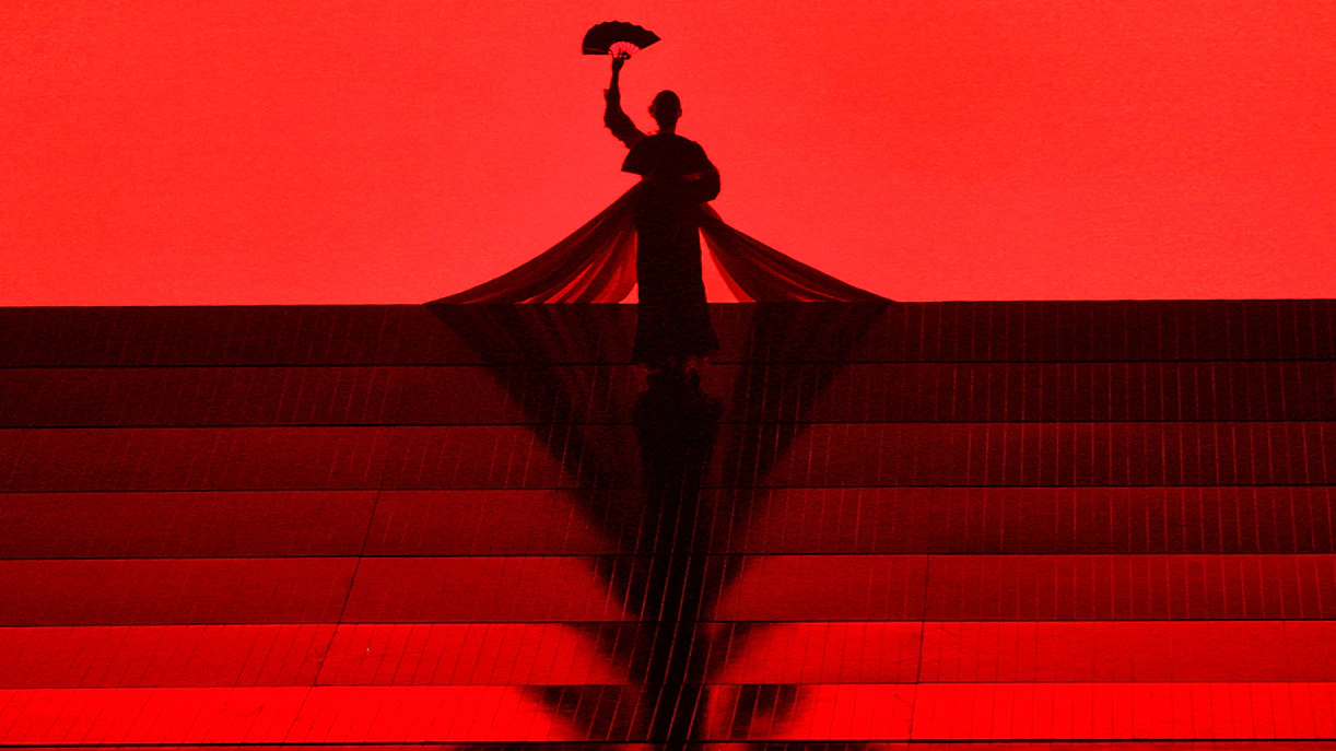 Silhouette of a performer holding a fan on stage during Madama Butterfly opera.