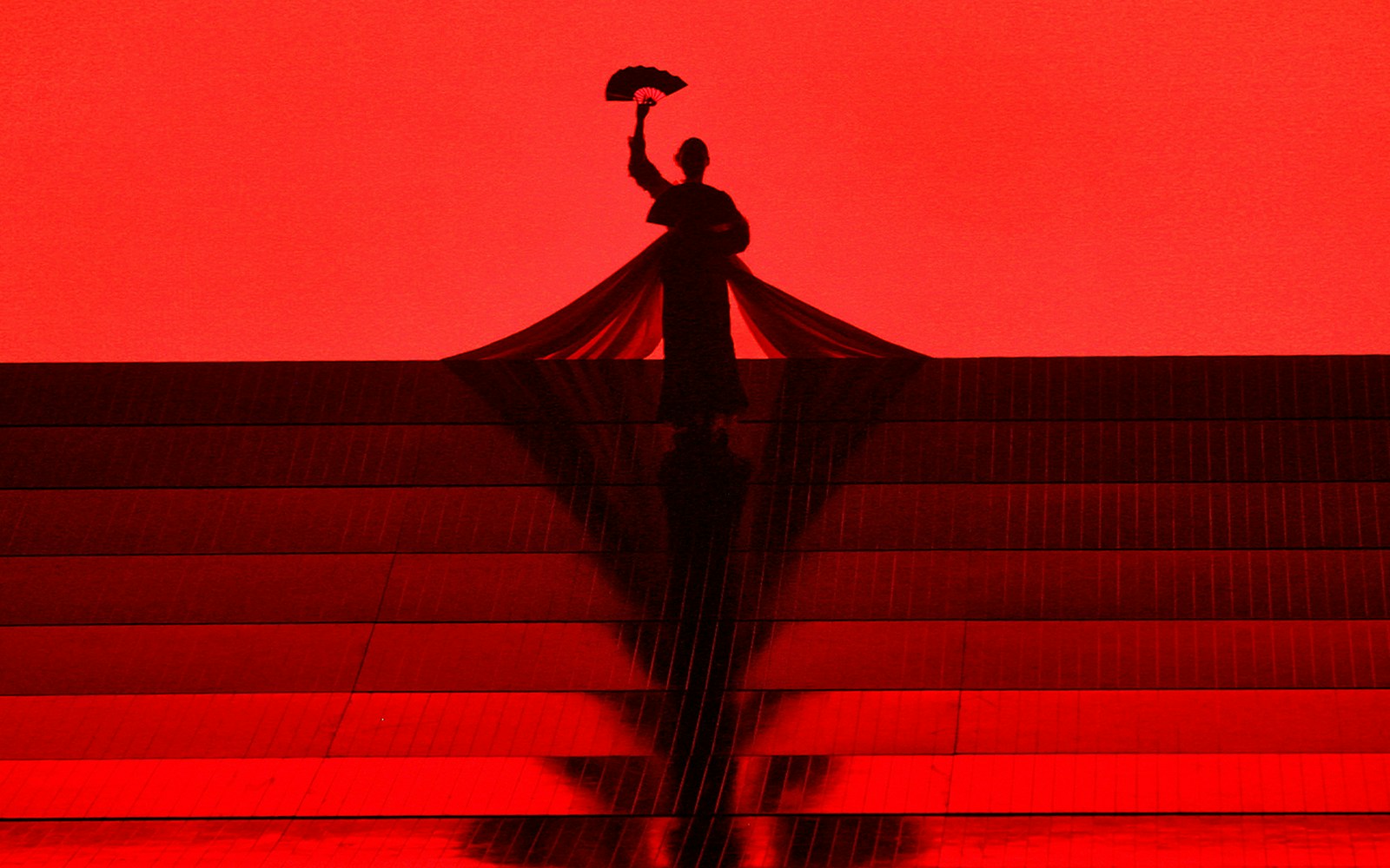Silhouette of a performer holding a fan on stage during Madama Butterfly opera.