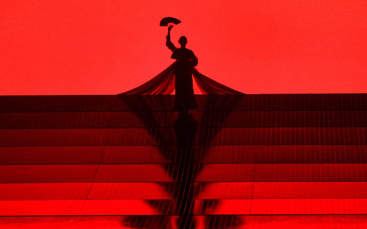 Silhouette of a performer holding a fan on stage during Madama Butterfly opera.