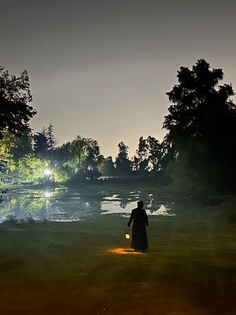 Silhouette of a person with a lantern by a lake at Viña Concha y Toro nighttime dinner show.