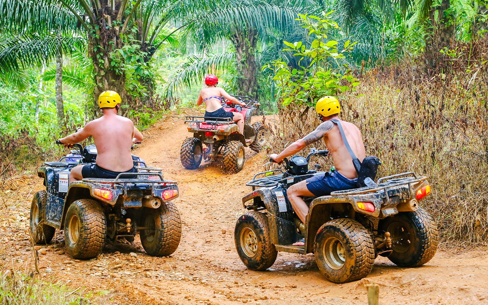 ATV riders navigating a dirt trail in Phuket's lush jungle.