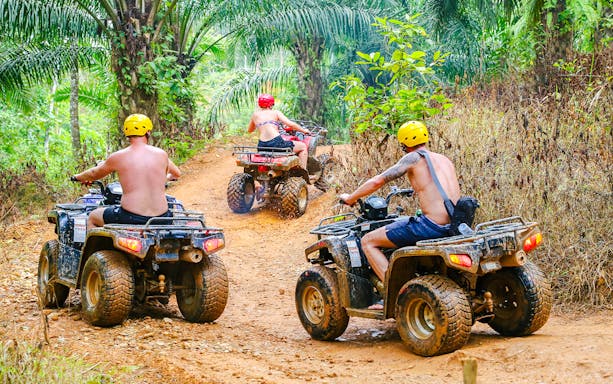ATV riders navigating a dirt trail in Phuket's lush jungle.
