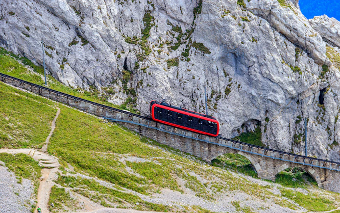 Red cogwheel train ascending Mount Pilatus near Lucerne, Switzerland.