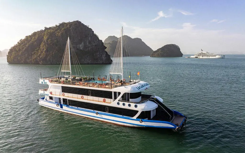 La Casta cruise ship sailing in Ha Long Bay with limestone islands in the background.