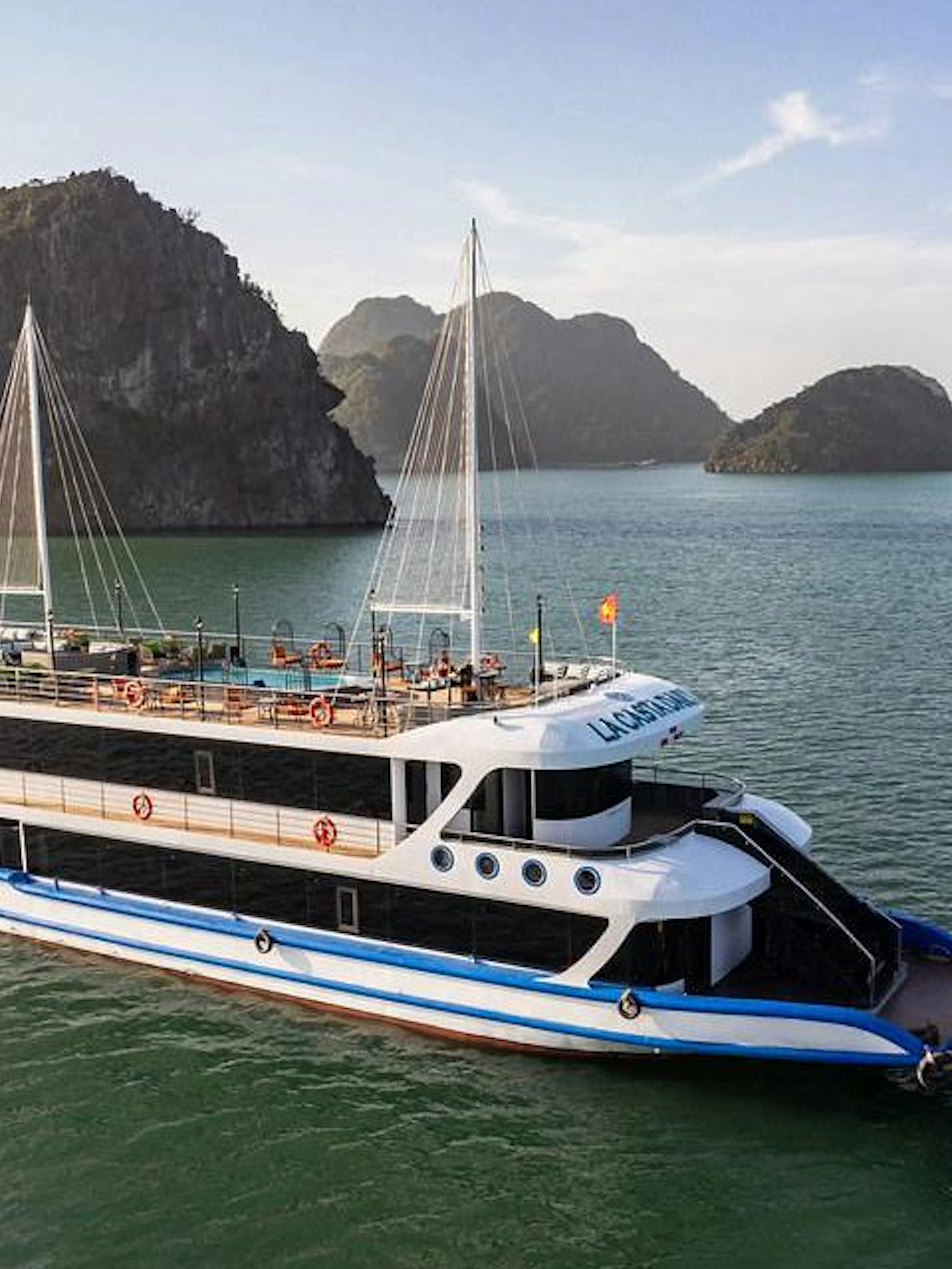 La Casta cruise ship sailing in Ha Long Bay with limestone islands in the background.