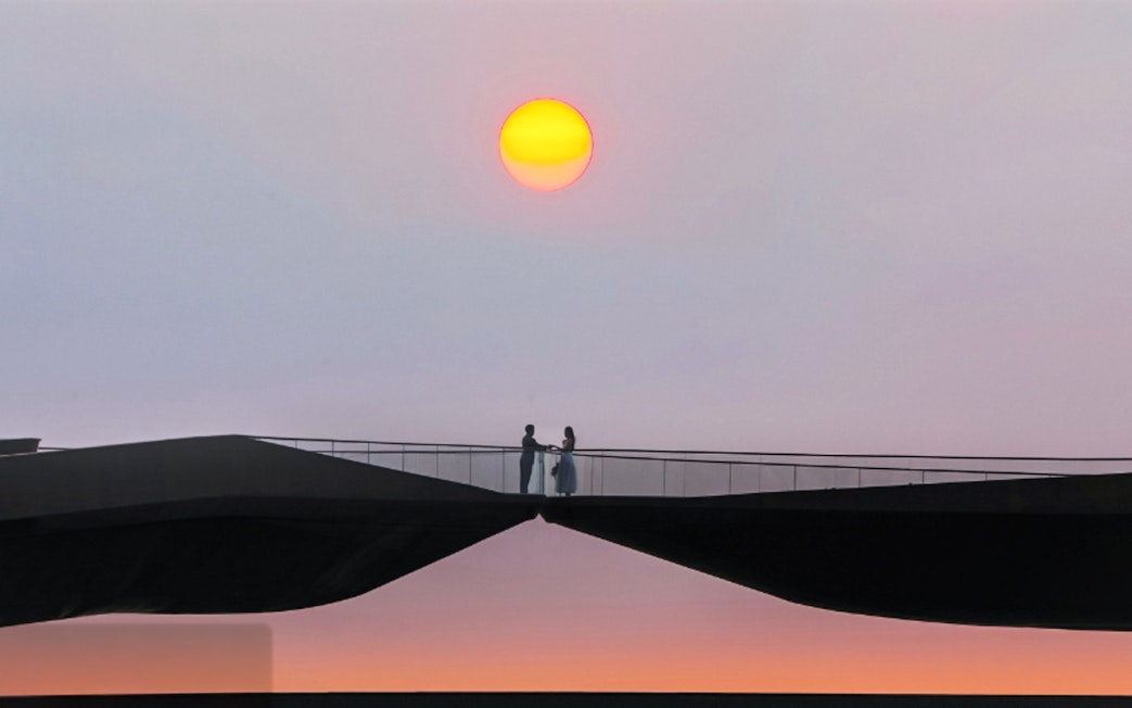 Couple standing on Kiss Bridge at sunset.