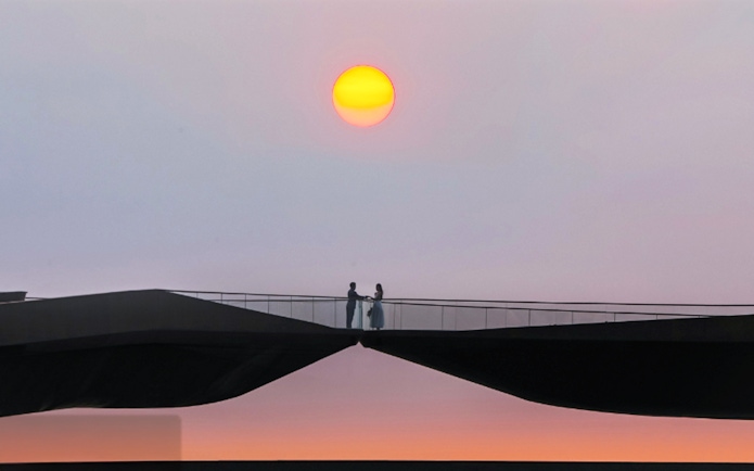 Couple standing on Kiss Bridge at sunset.