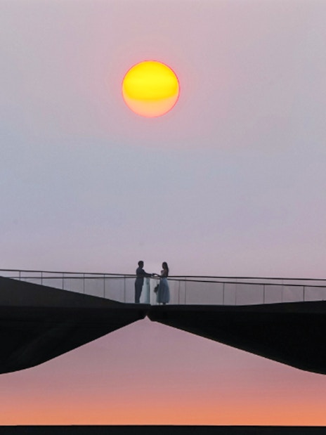 Couple standing on Kiss Bridge at sunset.