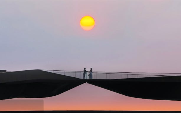 Couple standing on Kiss Bridge at sunset.