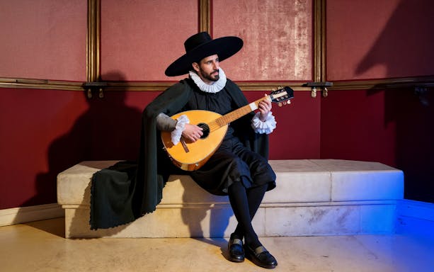 Male musician playing guitar at Alcazar of Seville night tour.