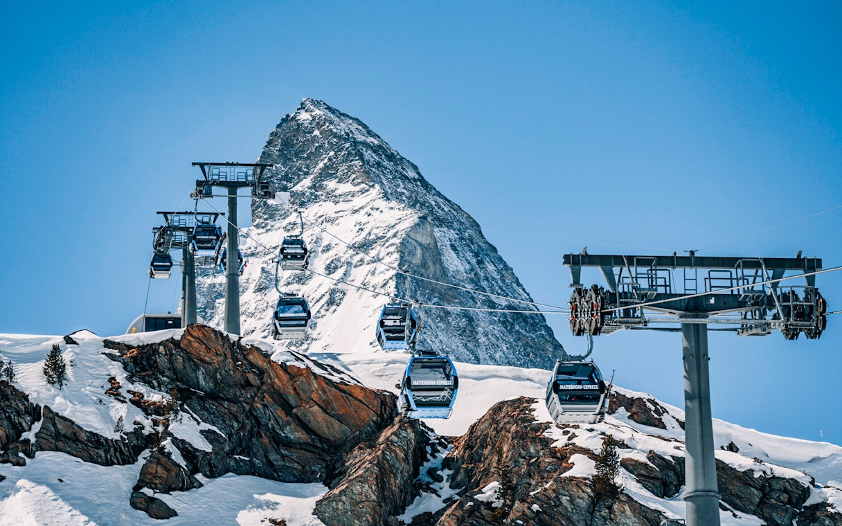Cable cars traveling to Matterhorn Glacier Paradise with snowy mountain backdrop.