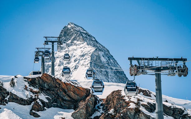 Cable cars traveling to Matterhorn Glacier Paradise with snowy mountain backdrop.