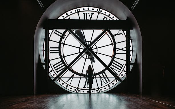 Visitor standing in front of the large clock at Orsay Museum, Paris.