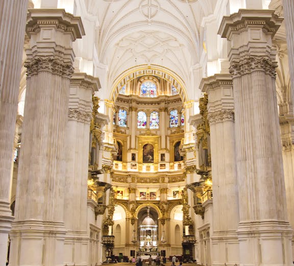 Granada Cathedral interior with ornate columns and stained glass windows.