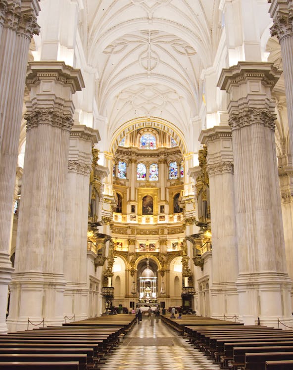 Granada Cathedral interior with ornate columns and stained glass windows.