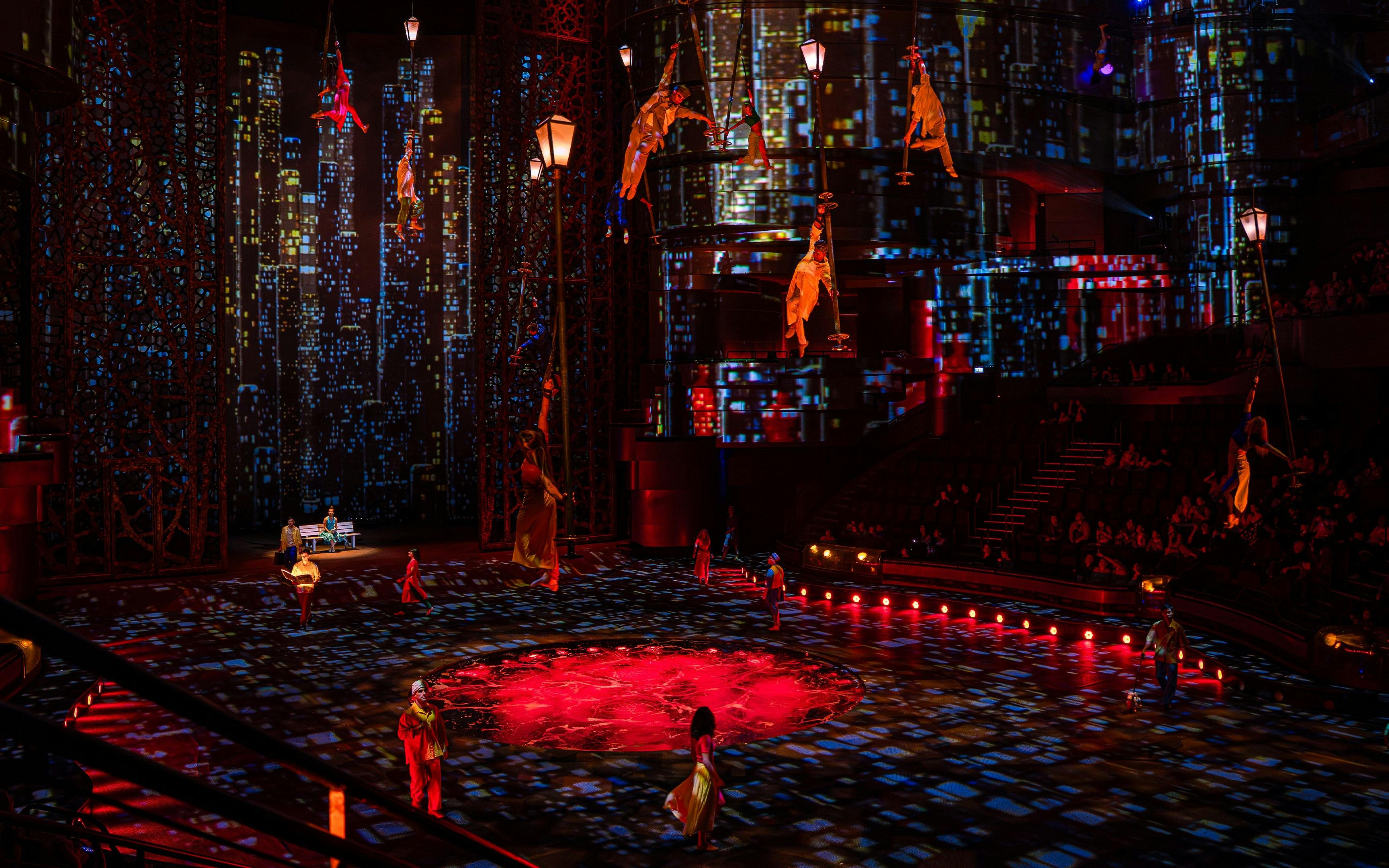 Acrobats performing in La Perle's City Rush show with vibrant cityscape backdrop.