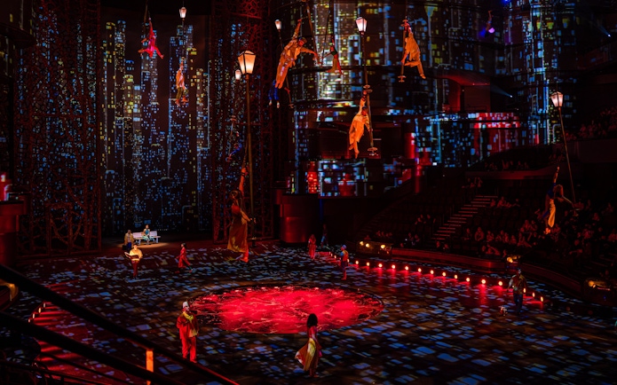 Acrobats performing in La Perle's City Rush show with vibrant cityscape backdrop.