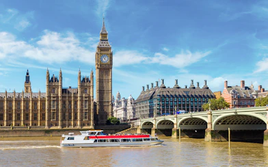 Westminster cruise boat on the Thames with Big Ben and bridge in view.