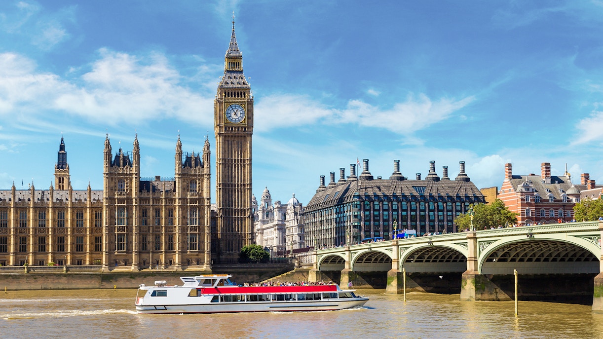 Westminster cruise boat on the Thames with Big Ben and bridge in view.