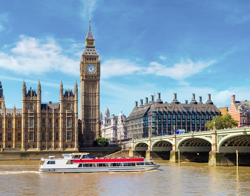 Westminster cruise boat on the Thames with Big Ben and bridge in view.